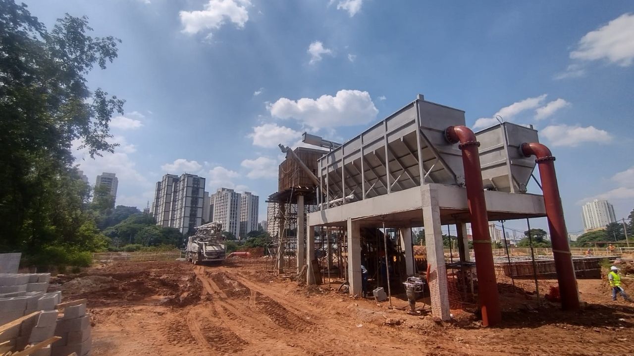 Equipamento industrial apoiado sobre estrutura elevada de concreto, com movimentação de terra em primeiro plano.
