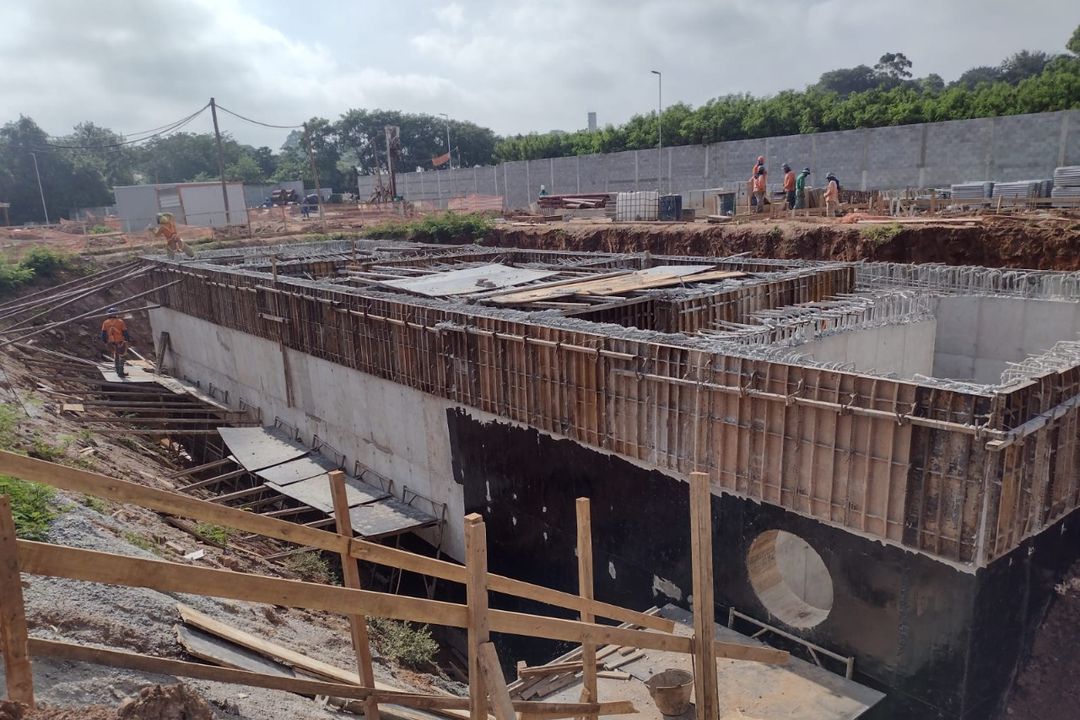 Estrutura enterrada de concreto armado com formas e impermeabilização, dentro de uma vala aberta.